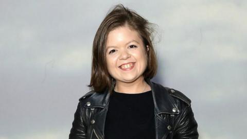 Sinead Burke, smiling and wearing a black top and leather jacket