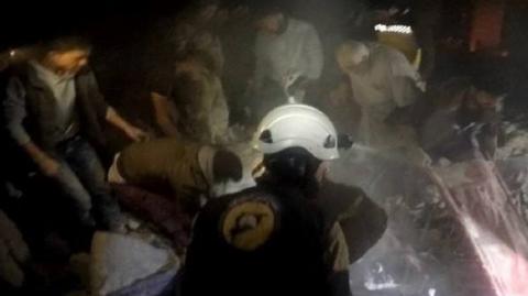 Photo posted by the Syria Civil Defence, also known as the White Helmets, purportedly showing rescue workers after air strikes on Maarshurin, in the Syrian province of Idlib (20 December 2017)