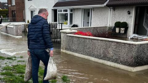 people carrying sandbags to homes 