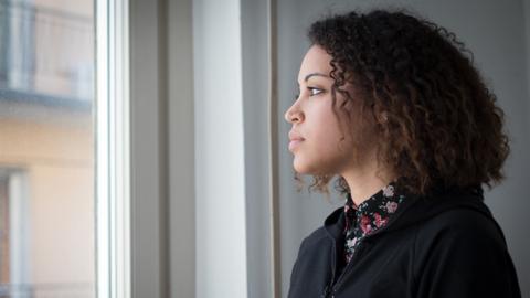 Young woman deep in thought looking out of a window