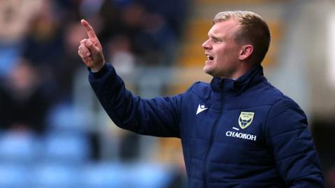 Oxford United boss Liam Manning communicates with his players on the pitch during a League One fixture.