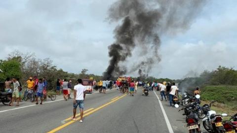 People watch as smoke billows from an overturned tanker truck that caught fire near Pueblo Viejo, Colombia. Photo: 6 July 2020