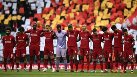 Liverpool players arm-in-arm during a minute's silence prior to the Arsenal game