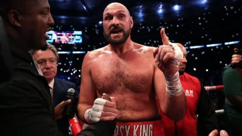 Tyson Fury holds up a finger as he speaks in the ring