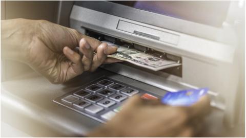 Stock image of person retrieving money from ATM