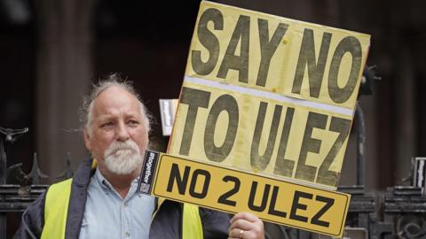 Man holds a 'Say no to ULEZ' placard
