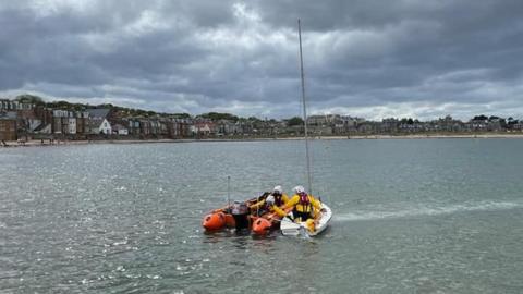 Dinghy being escorted to shore