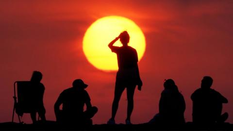 People turn out to watch the sunrise at Cullercoats Bay, North Tyneside on 19 July 2022