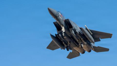 A US Air Force fighter jet flying through a clear blue sky.