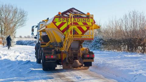 A gritter truck on a snowy road.