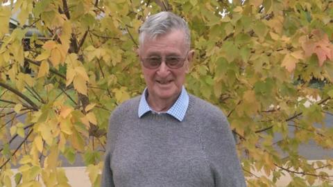 Denis Ryan standing in front of a tree