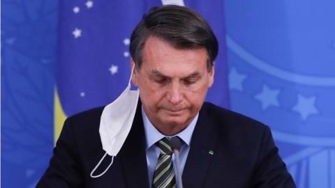 n this file photo taken on March 18, 2020 Brazilian President Jair Bolsonaro gestures during a press conference regarding the COVID-19 coronavirus pandemic at the Planalto Palace, Brasilia