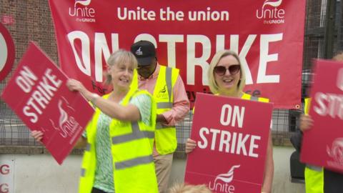 Survitec workers hold placards and dance on the picket line outside the company's factory in Dunmurry