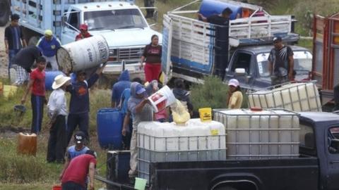 People fill large drums of fuel from a clandestine outlet, in the state of Puebla, Mexico, 23 October 2017