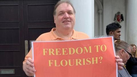 John Large holding placard