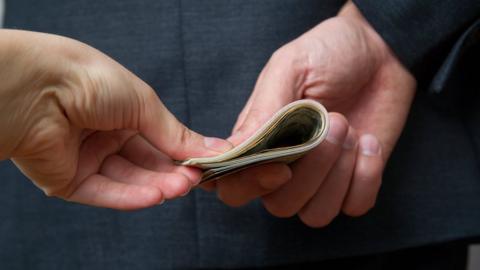 Businessman holding money behind his back