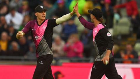 Kasey Aldridge, left, and Ben Green high-five after Aldridge takes a wicket for Somerset