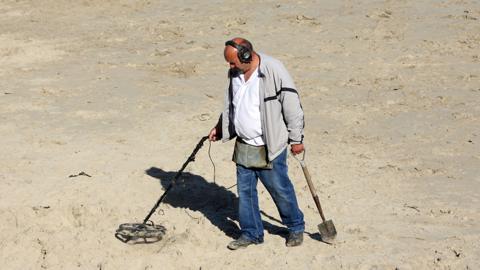 Metal detectorist on beach