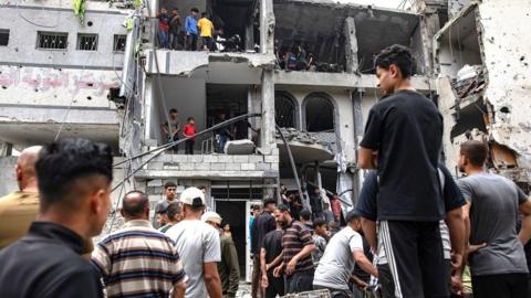 Palestinians inspect the Al-Tawba Medical Clinic building after it was hit by an Israeli airstrike in Jabalia in Gaza on 15 May