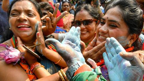 Indian supporters and party workers of Bharatiya Janata Party (BJP) put colour powder on their faces as they celebrate on the vote results day for India"s general election in Bangalore on May 23, 2019.