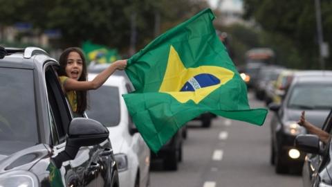 Supporters of presidential candidate for the Social Liberal Party (PSL) Jair Bolsonaro cheer in front of the residential condominium where he lives, in Barra da Tijuca, in Rio de Janeiro, Brazil, on October 7