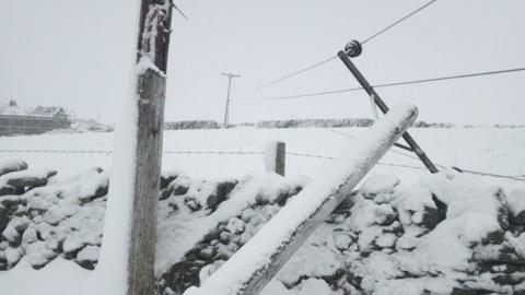 Broken power pole down in the snow