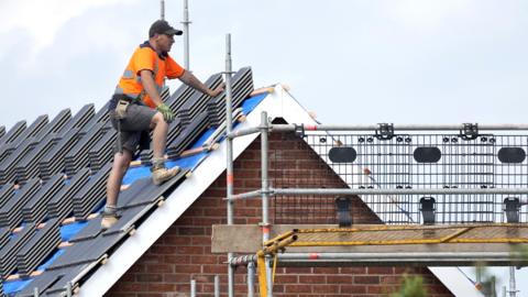 Builders work on a new housing construction development in June 2023 in Crewe, England