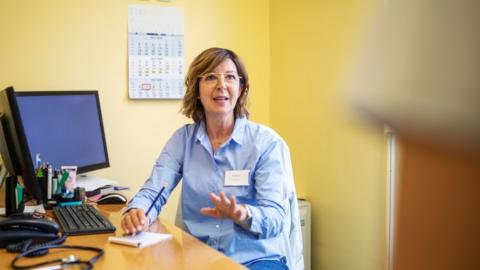 A GP in her surgery talking to a patient