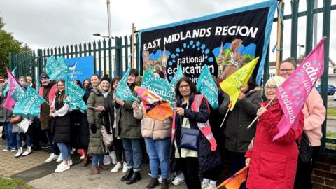 A group of teachers wave flags while striking