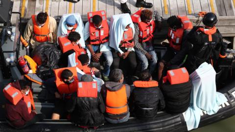 A group of people, thought to be migrants, waiting on a Border Force rib to come ashore at Dover marina