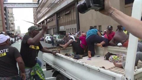 ANC supporters - one of them wielding a stick - are seen chasing away Black Land First activists