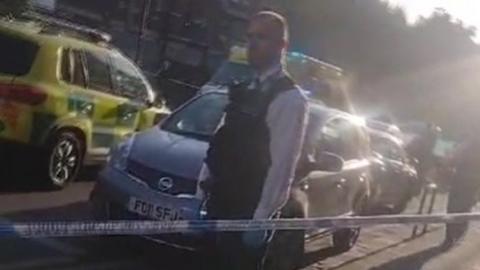 Police officer stands in front of emergency services' vehicles