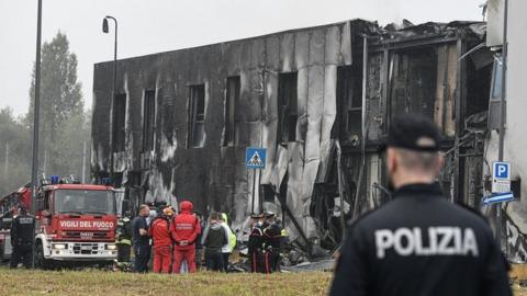A policeman looking at the building that a private jet crashed into