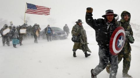 Veterans join activists in a march to Backwater Bridge just outside the Oceti Sakowin camp during a snow fall as "water protectors"