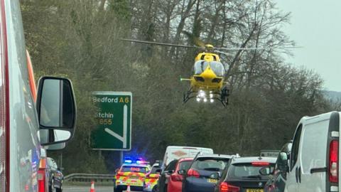 A helicopter hovers above the crash scene on the A6 in Bedfordshire