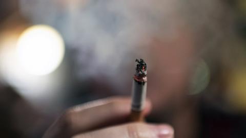 Cigarette being held and smoke obscuring a man's face