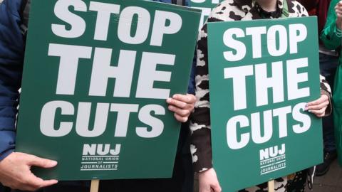 People protesting at BBC local radio cuts with placards reading "Stop the cuts"