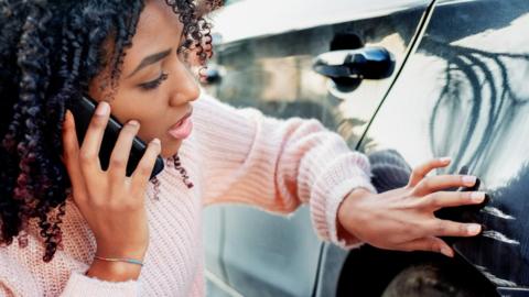 A woman calling her insurer after scratching her car