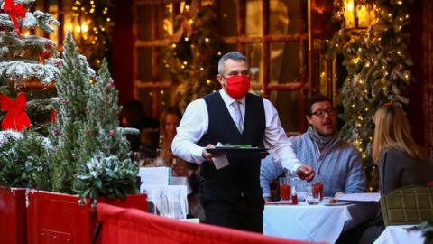 A waiter wearing a mask works at a restaurant in London