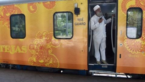 In this photograph taken on May 21, 2017, an Indian guard communicates with the driver during a trial of the Tejas Express luxury train the Tejas Express luxury train before its first journey between Mumbai and Goa at the Chattrapati Shivaji Terminus terminus station in Mumbai.