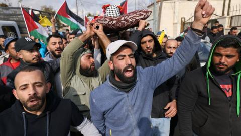 Palestinian mourners carry the body of Ahmad Kahla during his funeral in the village of Rammun, in the occupied West Bank, on 15 January 2023