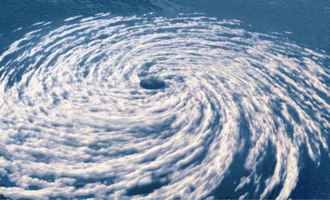 Blue sea under the white cloud of a hurricane swirling round the eye of the storm