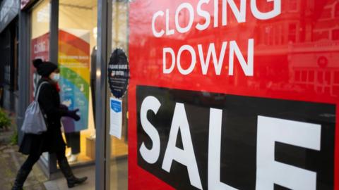 A woman walks into a shop with a closing down sale