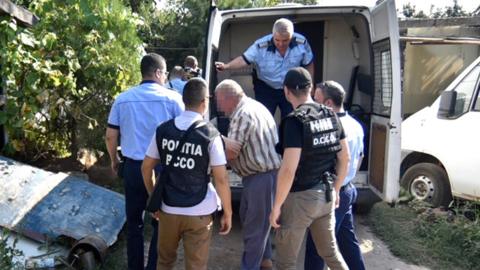 Romanian police officers escort suspect Gheorghe Dinca (C) to his home for a search of the property in relation to the kidnapping of a 15-year-old girl in the southern city of Caracal, Romania, 27 July 2019