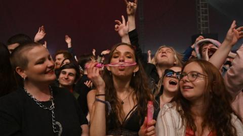 Three women at the front of a crowd in a concert