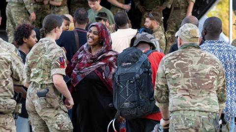 Evacuees with soldiers boarding an evacuation flight in Sudan