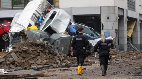 Police walk past debris in the spa town of Bad Neuenahr