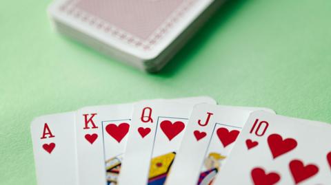 A stock photo of a Royal Flush poker card sequence on a green table.