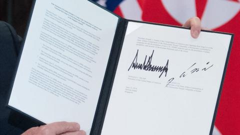 US President Donald Trump holds up a document signed by him and North Korea's leader Kim Jong Un following a signing ceremony during their historic US-North Korea summit