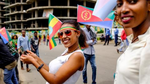 A woman takes a selfie while holding on her head the flags of Eritrea and Ethiopia - 14 July